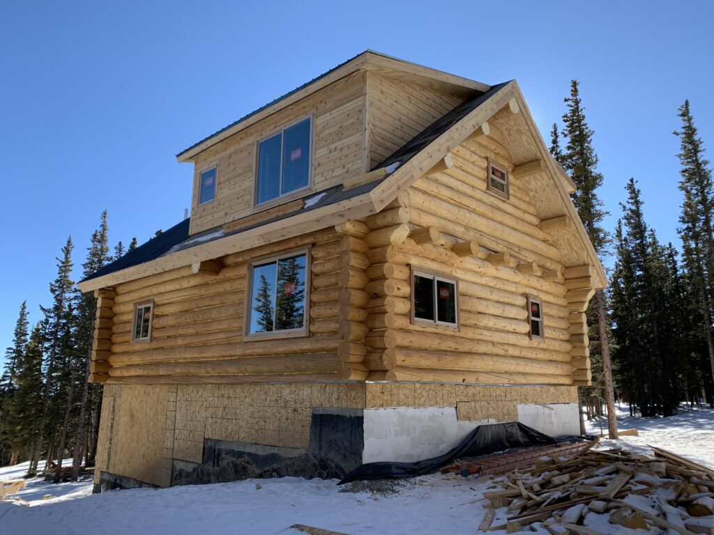 Natural oak cabin beside mature trees and snow