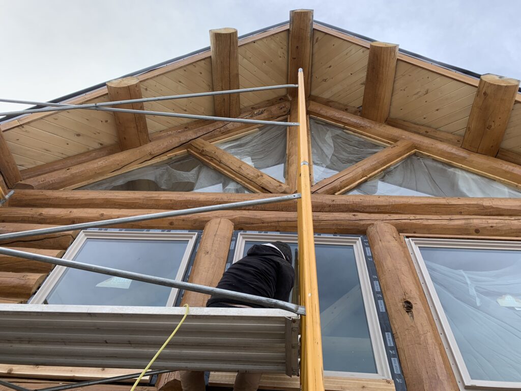 Man installing windows on multi-story log cabin