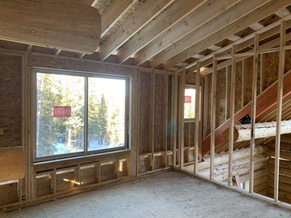 Framework for upstairs rooms in log cabin beside wooden staircase