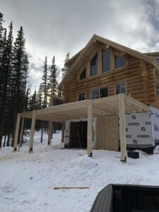 Three-story cabin with partially completed wooden deck and oversized garage