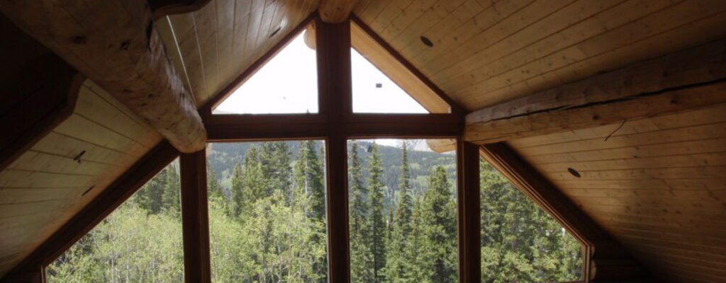 Vaulted wooden ceiling and multistory windows overlooking forest and mountains