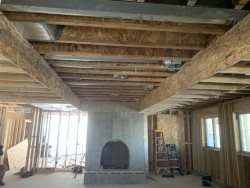 Framework of custom home under construction with stone fireplace opening