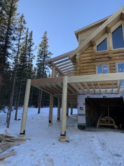 Partially constructed wood deck beside wood cabin with oversized garage