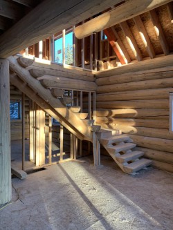 Log cabin under construction with unfinished floors and interior walls