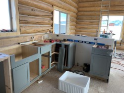 Kitchen remodel in log cabin with partially-assembled blue painted cabinets