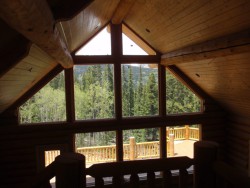 Vaulted wood ceiling and large windows overlooking forest and Rocky Mountains