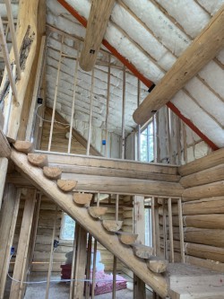 Log staircase and wooden support beams inside partially-built wood cabin