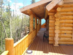 Wooden deck on second story of log cabin overlooking forest
