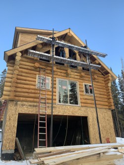 Large wood cabin under construction beside metal support beams