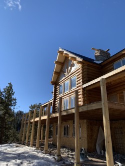 Wooden support beams for partially-completed wood deck of log cabin