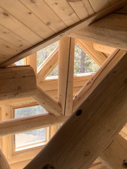 Pine wood support beams and paneled ceiling in multistory log cabin