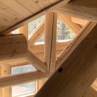 Pine wood support beams and paneled ceiling in multistory log cabin