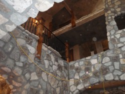 Three-story cabin with open ceilings, stone walls and black metal railings