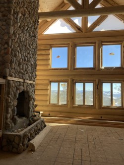 Stone fireplace in cabin with vaulted ceilings and large windows