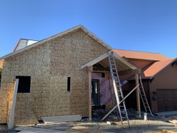 Partially constructed home addition beside cabin garage