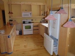 Kitchen with yellow walls, pine wood cabinetry and red hanging lights