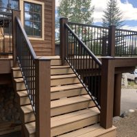 Staircase to large wooden deck with black metal railings
