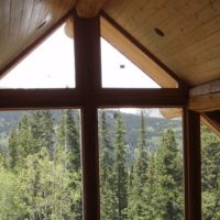 Vaulted wooden ceiling and multistory windows overlooking forest and mountains